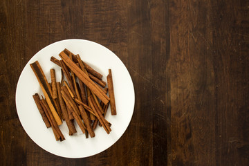 Cinnamon Sticks And White Plate On Wood Tabletop