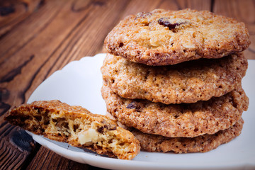 Oat cookies with raisins and nuts on a brown wooden table