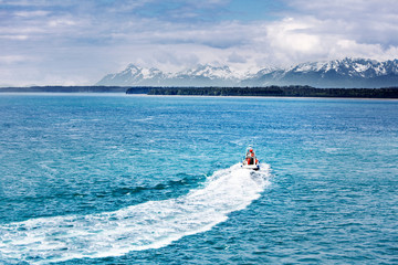 Curved wake of a boat speeding away toward the mountains and wilderness, Glacier Bay National Park, Alaska