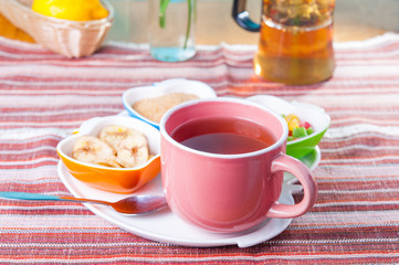 Cup of hot tea with snacks on a tray on the served table. Relax breakfast concept. Selective focus