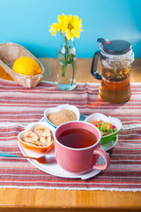 Cup of hot tea with snacks on a tray on the served table. Relax breakfast concept. Selective focus