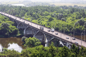 Tilt and shift view aeral view of a river arch stone bridge with many moving cars