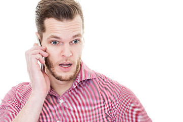 Obraz premium Young shocked man talking on his mobile phone isolated on white