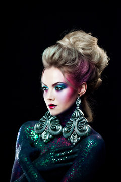 Young attractive blonde girl in bright art-makeup, high hair, body painting. Rhinestones and glitter