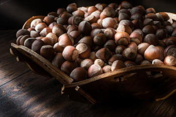 Stack of Hazelnuts in wooden bowl. (dim light)