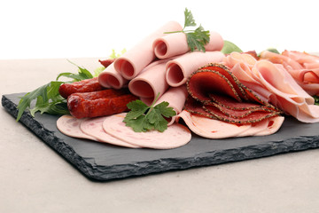 Food tray with delicious salami, pieces of sliced ham, sausage, tomatoes, salad and vegetable - Meat platter with selection