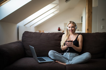 Obraz premium Blonde woman relax at home listening music in headphones and drink tea