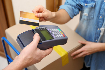 Young woman paying for parcel received from courier, closeup