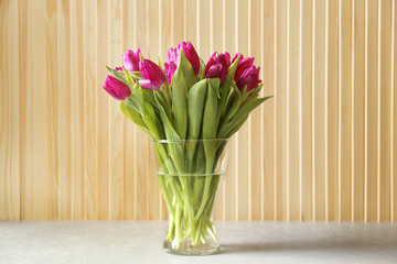Glass vase with bouquet of beautiful tulips on wooden  background