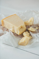 Italian parmesan cheese. Pieces of Parmesan cheese on white wooden table. Parmesan cheese