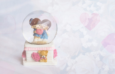 lovely couple dolls in glass ball with blurry roses for valentine background, filtered tones