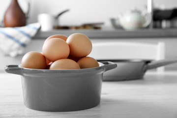 Raw eggs in saucepan on kitchen table