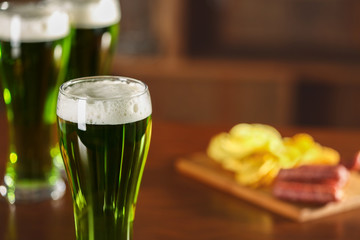 St. Patrick Day concept. Glass of green beer and snacks on bar counter