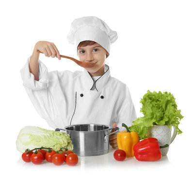 Cute boy in chef uniform preparing tasty soup, on white background