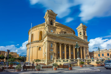 Obraz premium Mosta, Malta - The Church of the Assumption of Our Lady, commonly known as the Rotunda of Mosta or Mosta Dome at daylight with moving clouds and blue sky