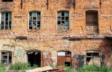 facade of the old red brick building with broken windows and traces of vandalism