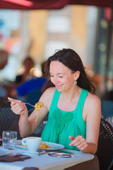 Young woman eating spaghetti at outdoor cafe on italian vacation