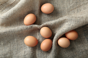 Raw eggs on sack fabric background