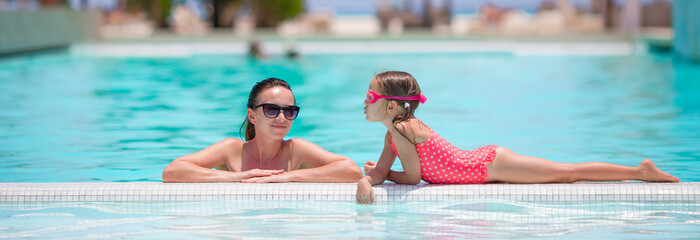 Family enjoying summer vacation in luxury swimming pool
