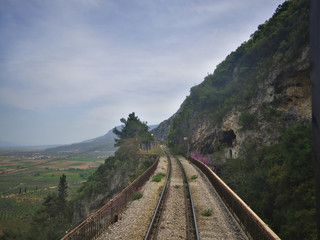 Fototapeta na wymiar View through rear window of train travelling through mountains..