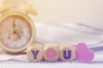 blurry picture of lovely wood blocks with vintage alarm clock for valentine background, filtered tones