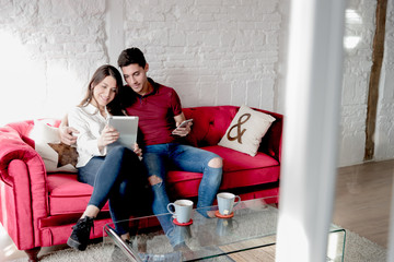 Happy young couple relaxed and having fun at home with tablet