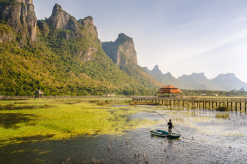 A man paddles up in the national park with mountains and boardwalk in the background.