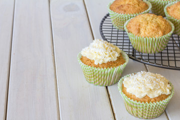 Coconut Snowball Cupcakes from the Front on White Wooden Table with Copy Space Left Horizontal