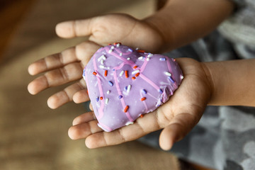Heart shaped biscuit cookie in child’s hands, selective focus
