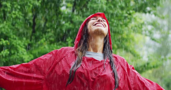 girl smiles, spins and laughs in the rain. the rain falls, the drops fall on his face and the girl is happy with life and nature around. concept of nature and happy life. Adventure, purity.