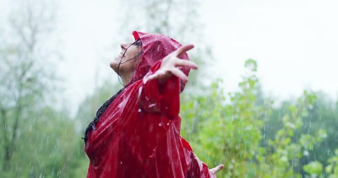 girl smiles, spins and laughs in the rain. the rain falls, the drops fall on his face and the girl is happy with life and nature around. concept of nature and happy life. Adventure, purity.