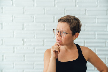 Young attractive girl with glasses and a freelancer short hair do makes thoughtful face. Thoughts,...
