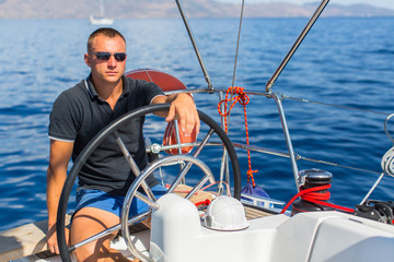 Captain at the helm controls of a sailing boat during sea yacht race.