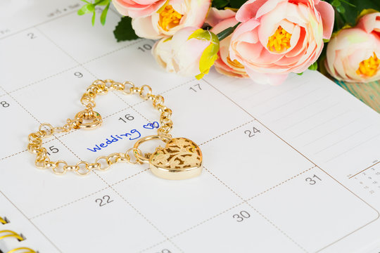 word wedding on calendar and gold bracelet with heart
