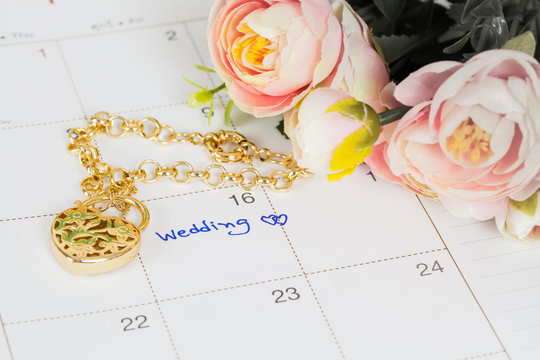 word wedding on calendar and gold bracelet with heart