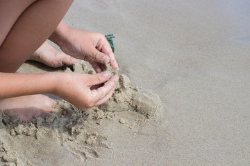 Child's hand playing in the sand of the sea