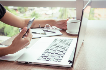 Close Up of woman hands using mobile phone and laptop computer with blank copy space screen for your advertising text message or content business in the Vintage effect.