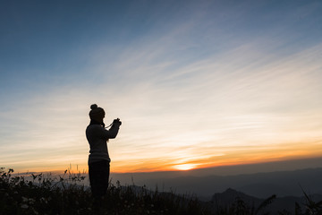 Fototapeta na wymiar Photographer Silhouettes On Cliff Against Colorful Twilight Sky