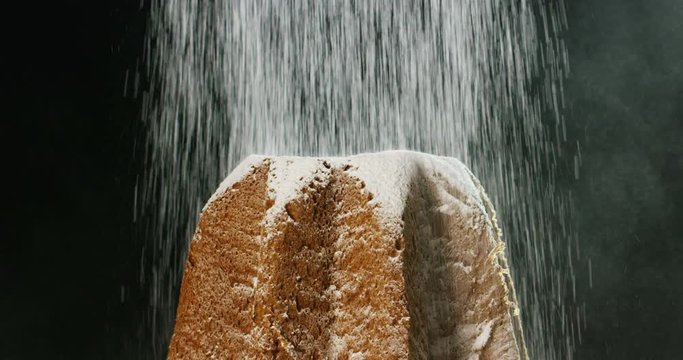 close up of a Pandoro, a typical Italian pastry eaten during the Christmas holidays and the New Year, The powdered sugar falls in slow motion on Pandora creating the Christmas magic.