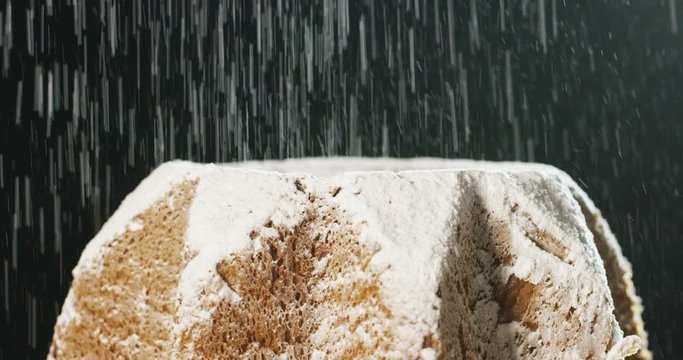 close up of a Pandoro, a typical Italian pastry eaten during the Christmas holidays and the New Year, The powdered sugar falls in slow motion on Pandora creating the Christmas magic.