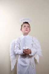 Boy dressed as an angel holding a candle