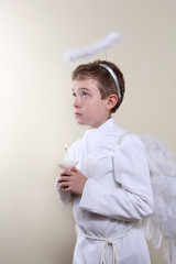 Boy dressed as an angel holding a candle