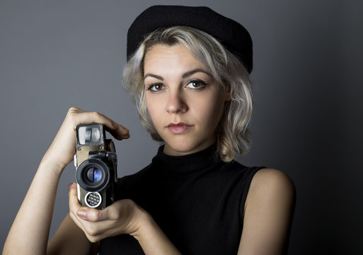 Woman Holding A Vintage Video Camera Posing As A Director, Filmmaker, Or Cinematographer In The Hollywood Movie Industry.  The Image Depicts Creative Arts.