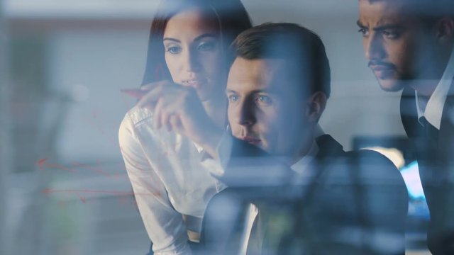 The three workers stand over the glass board and discuss graph