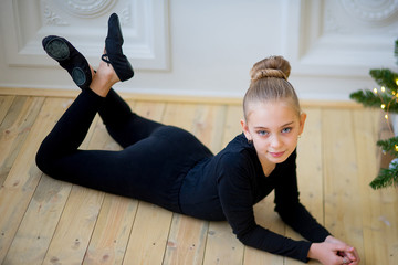 Young ballet dancer lying near the wall