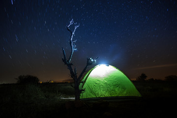 A tent in the woods under a star filled sky.