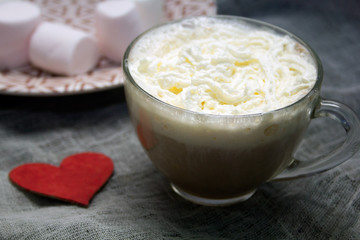creamy cappuccino in a glass mug and marshmallows