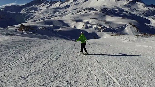 Slow motion: Young woman is skiing down on slope on sunny day, Tignes, France