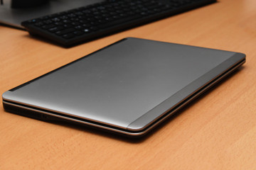 Sleek stylish silver ultra notebook on desk. Computer second.
