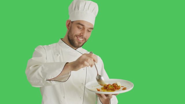 Mid Shot of a Handsome Chef Holding Plate With Dish Decorating Dish with a Spoon. Shot with Green Screen Background.  Shot on RED Cinema Camera 4K (UHD).